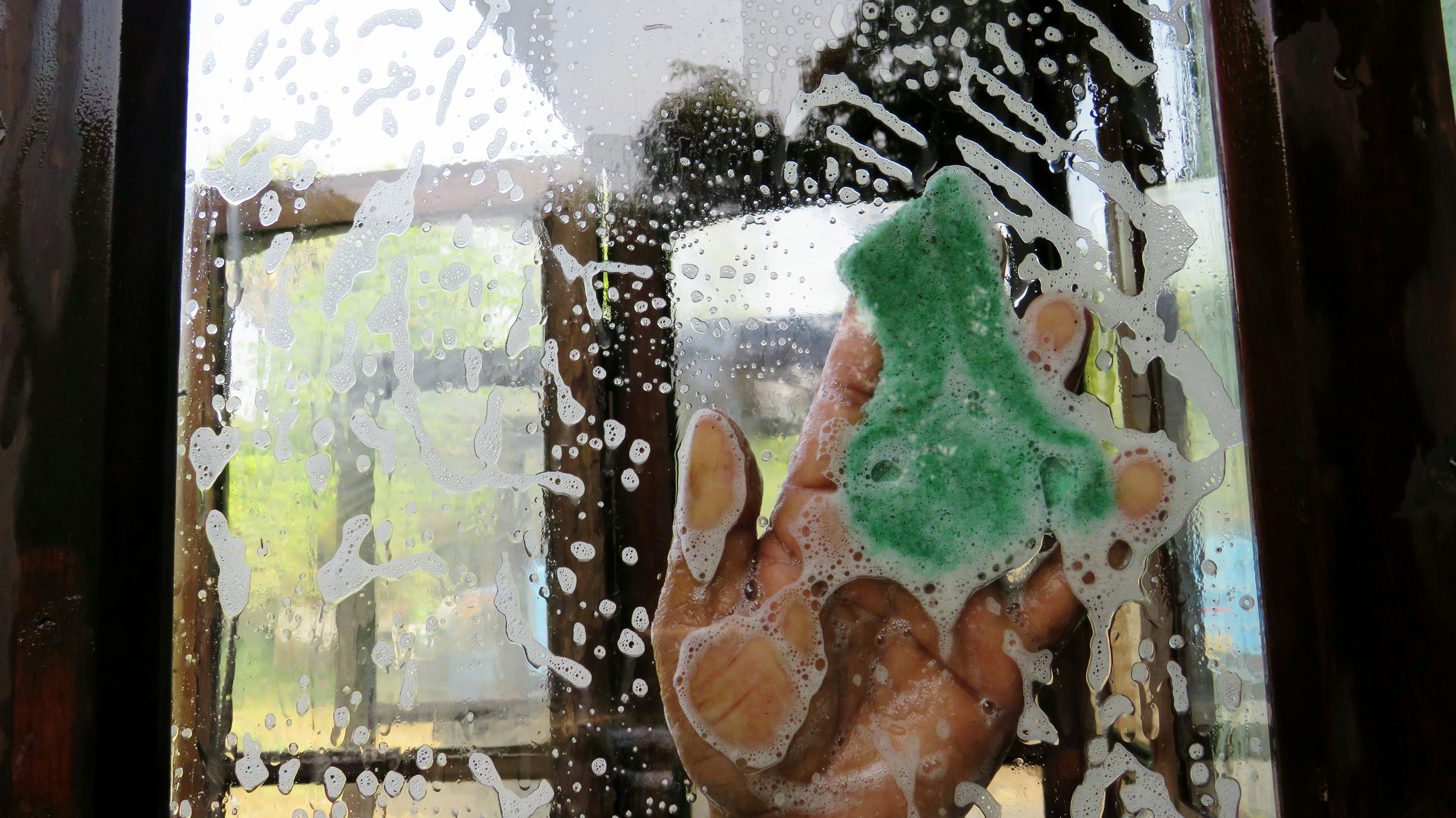 Professional window cleaning with sponge and soap