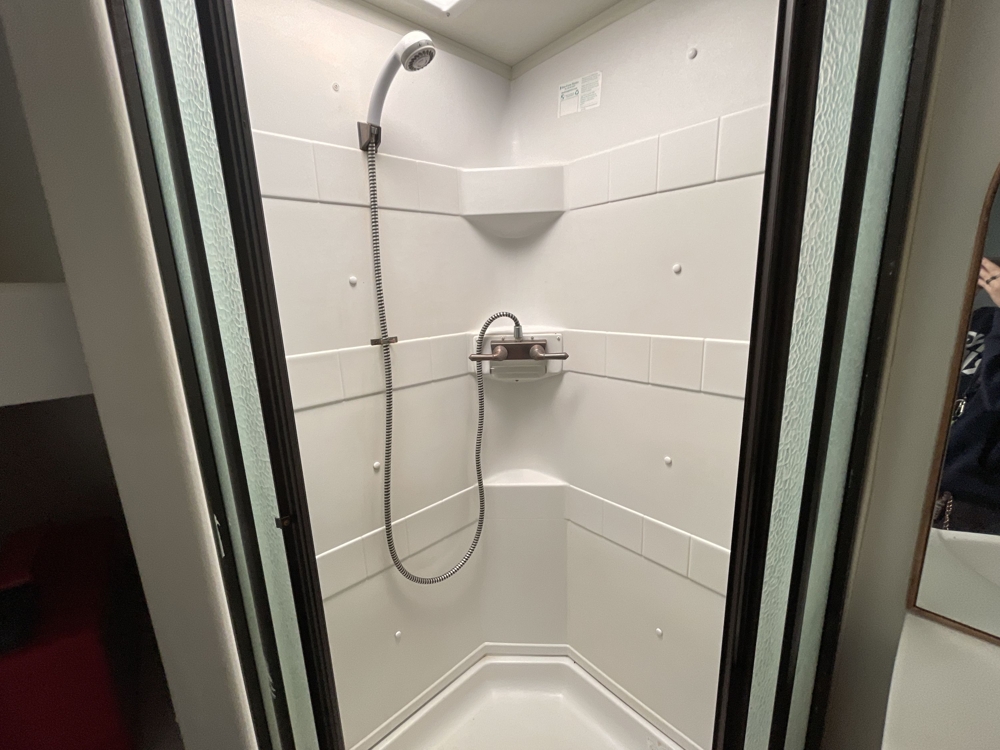 Clean modern RV shower with tiled walls and handheld shower head