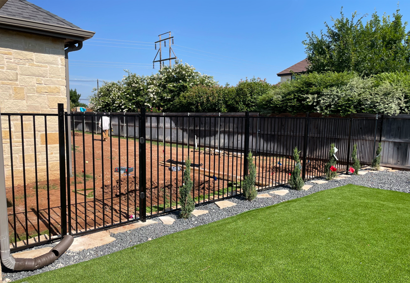 Black ornamental metal fence in residential backyard
