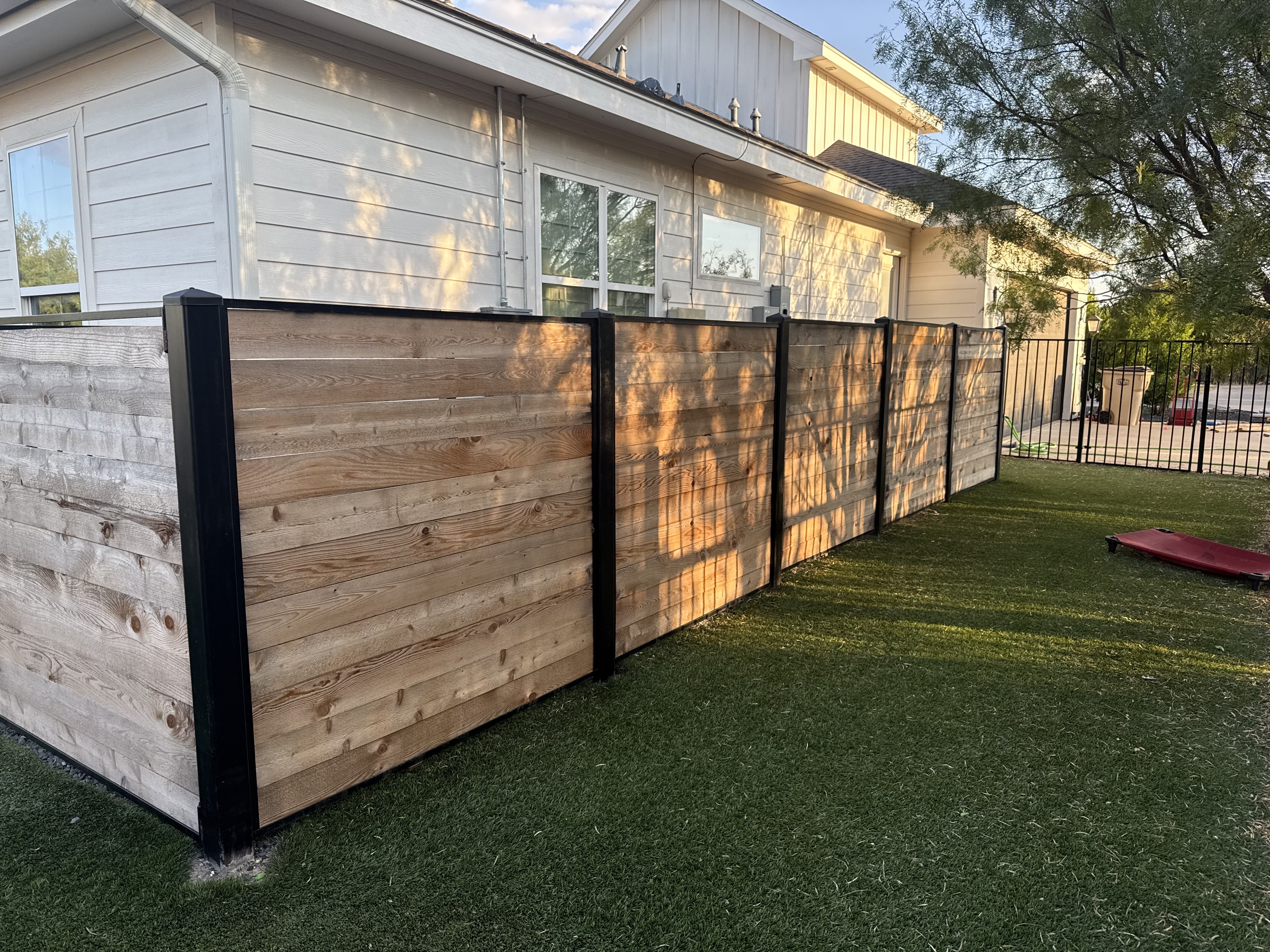 Horizontal wood privacy fence with black metal posts
