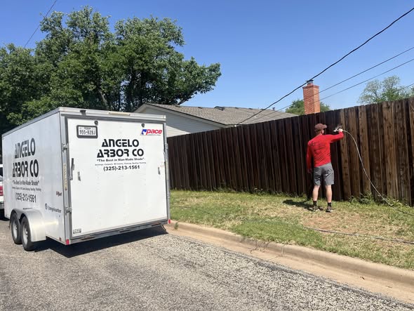 Angelo Arbor Co trailer and worker staining fence in San Angelo
