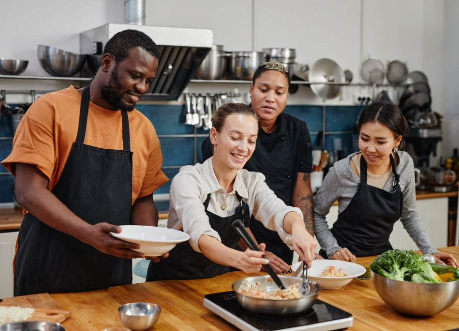 Diverse group of people participating in a cooking workshop in a professional kitchen setting