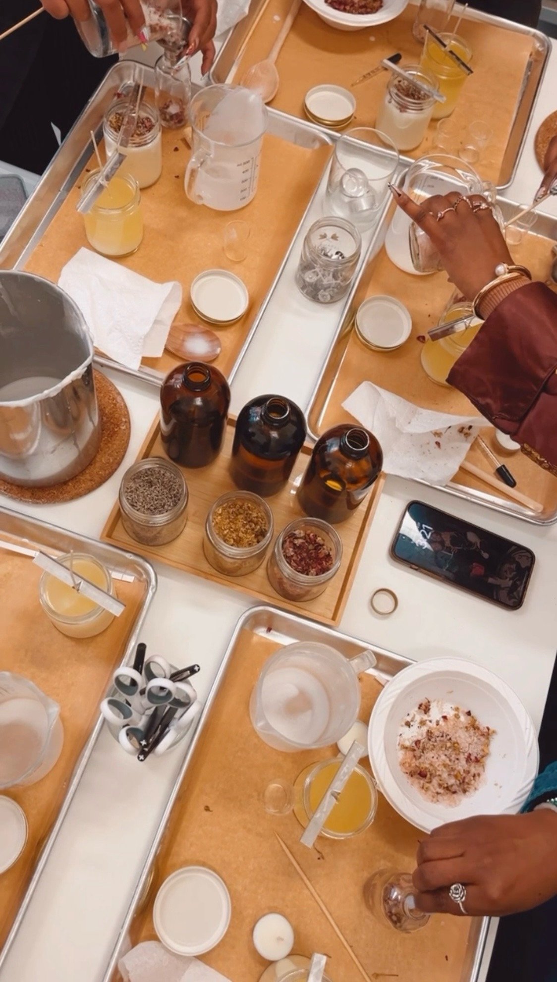 Overhead view of fragrance workshop ingredients with hands working with bottles, oils, and materials