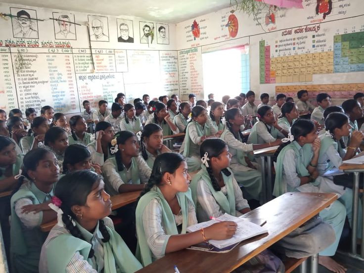 Well-organized classroom with proper desks, educational charts on walls, and students in uniforms