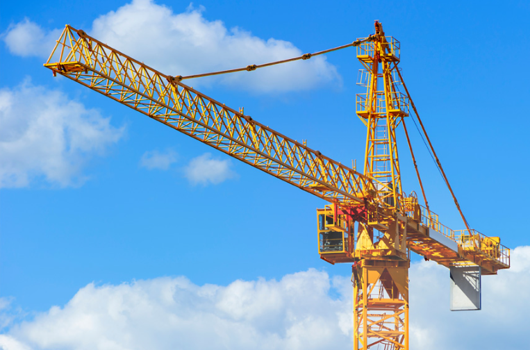 Yellow tower crane against blue sky