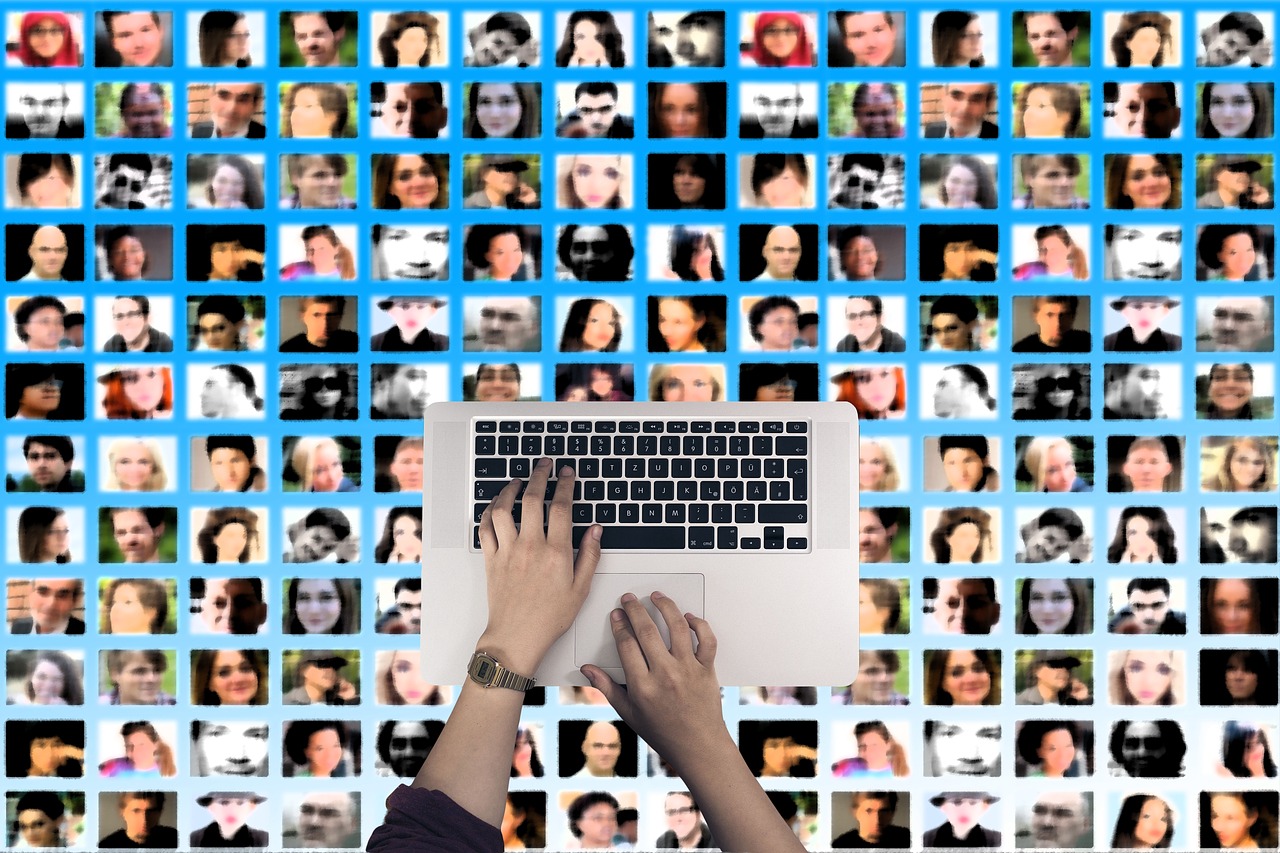 Hands typing on laptop with grid of social media profiles, representing digital content creation