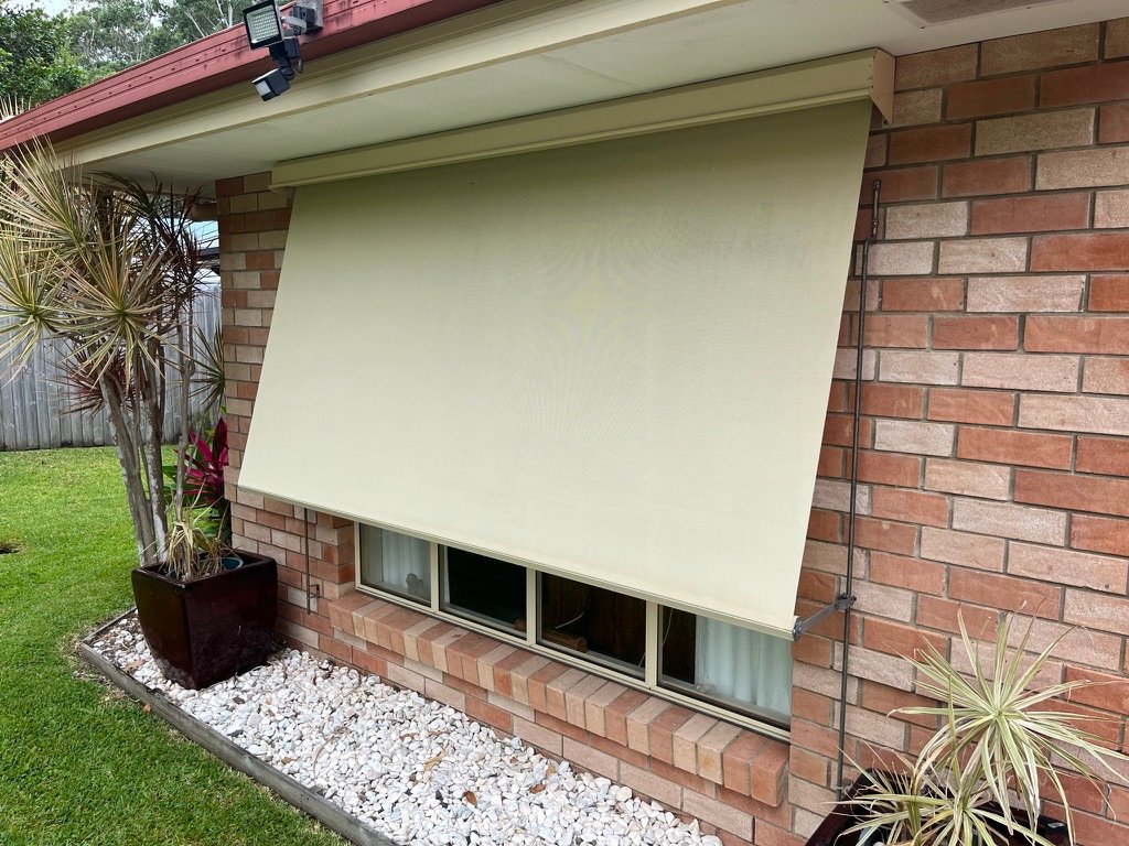 Fixed guide awning with cream fabric on brick home