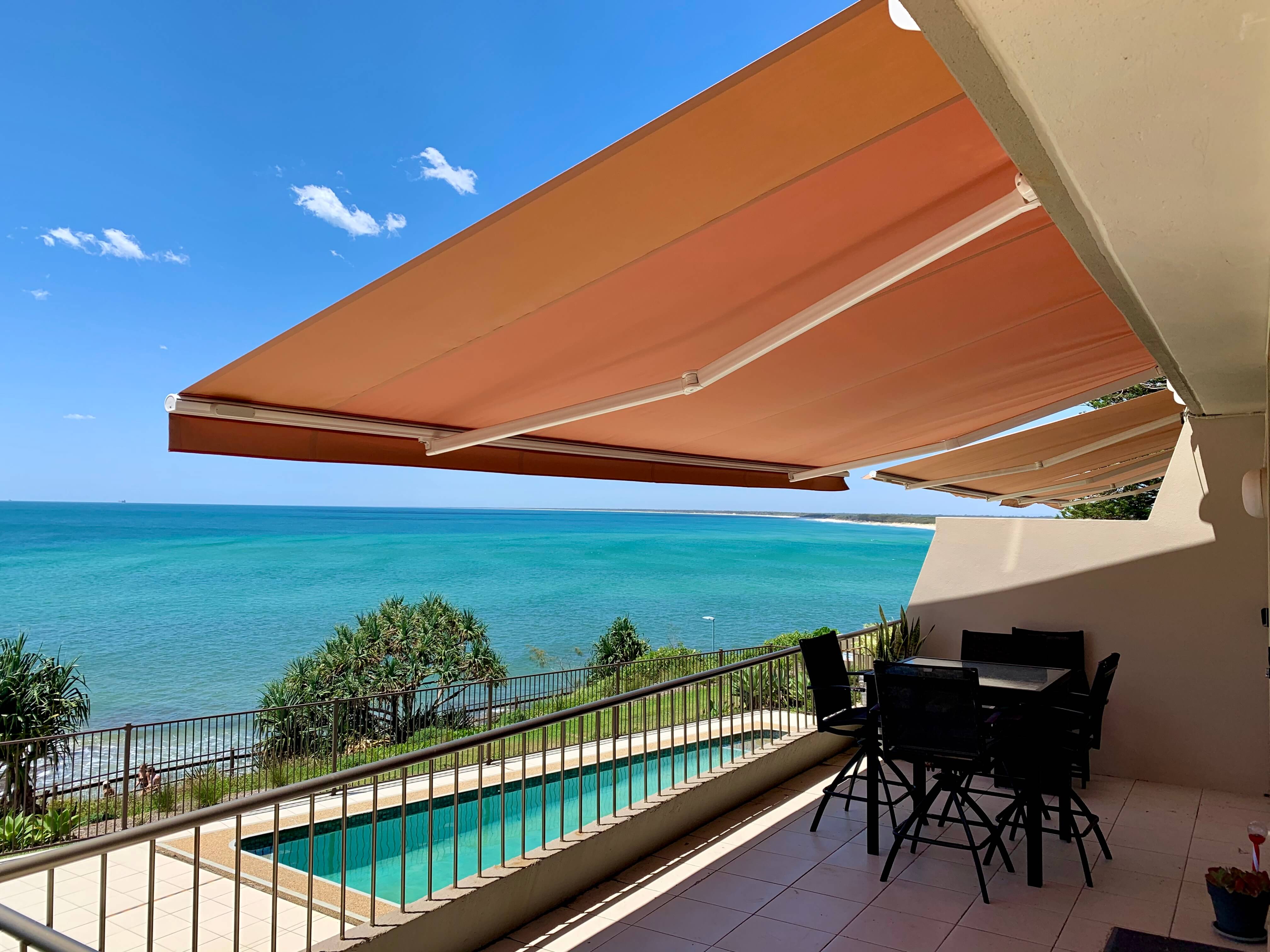 Orange standard awning extended over an oceanfront balcony