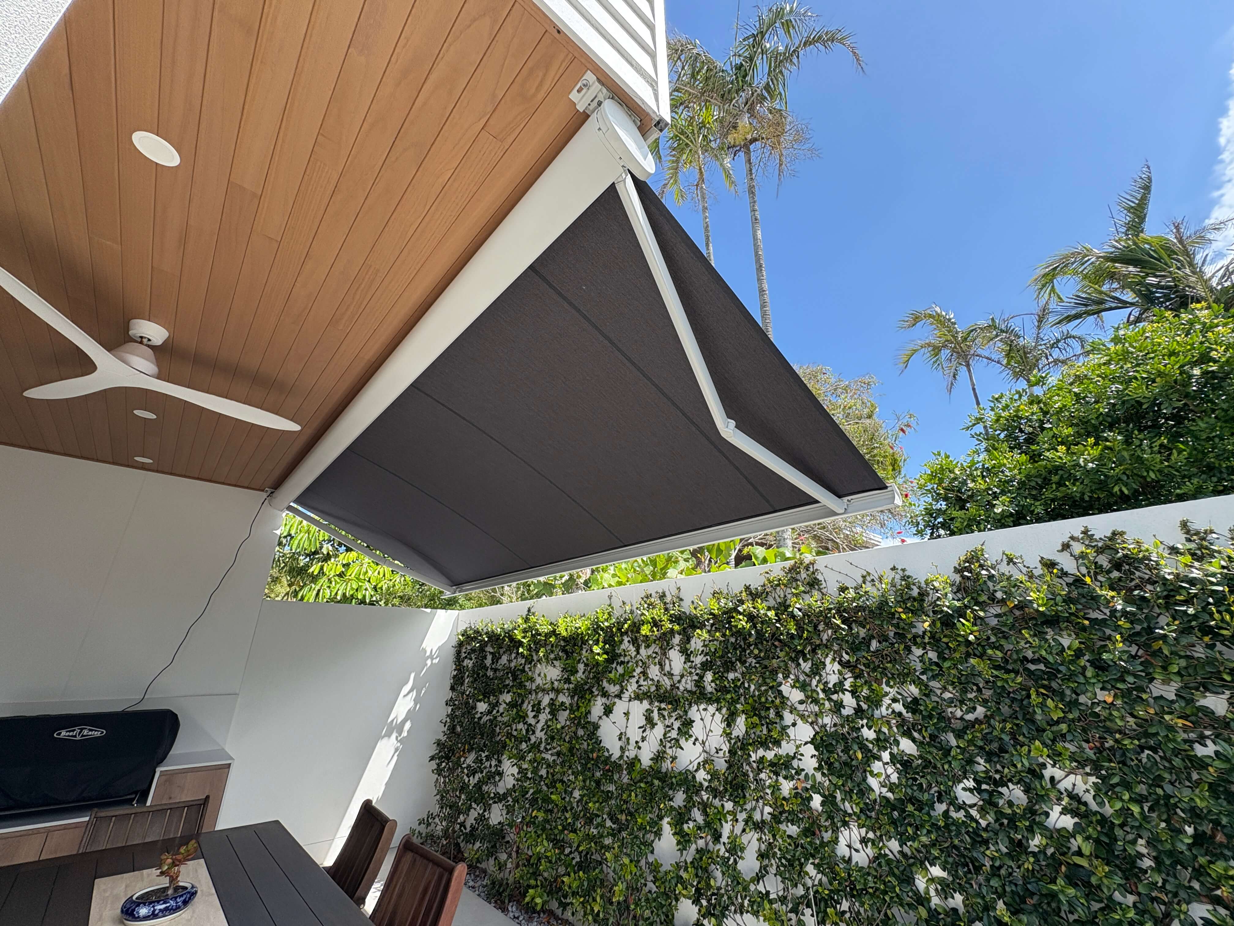 Full cassette folding arm awning extending over a lush garden patio