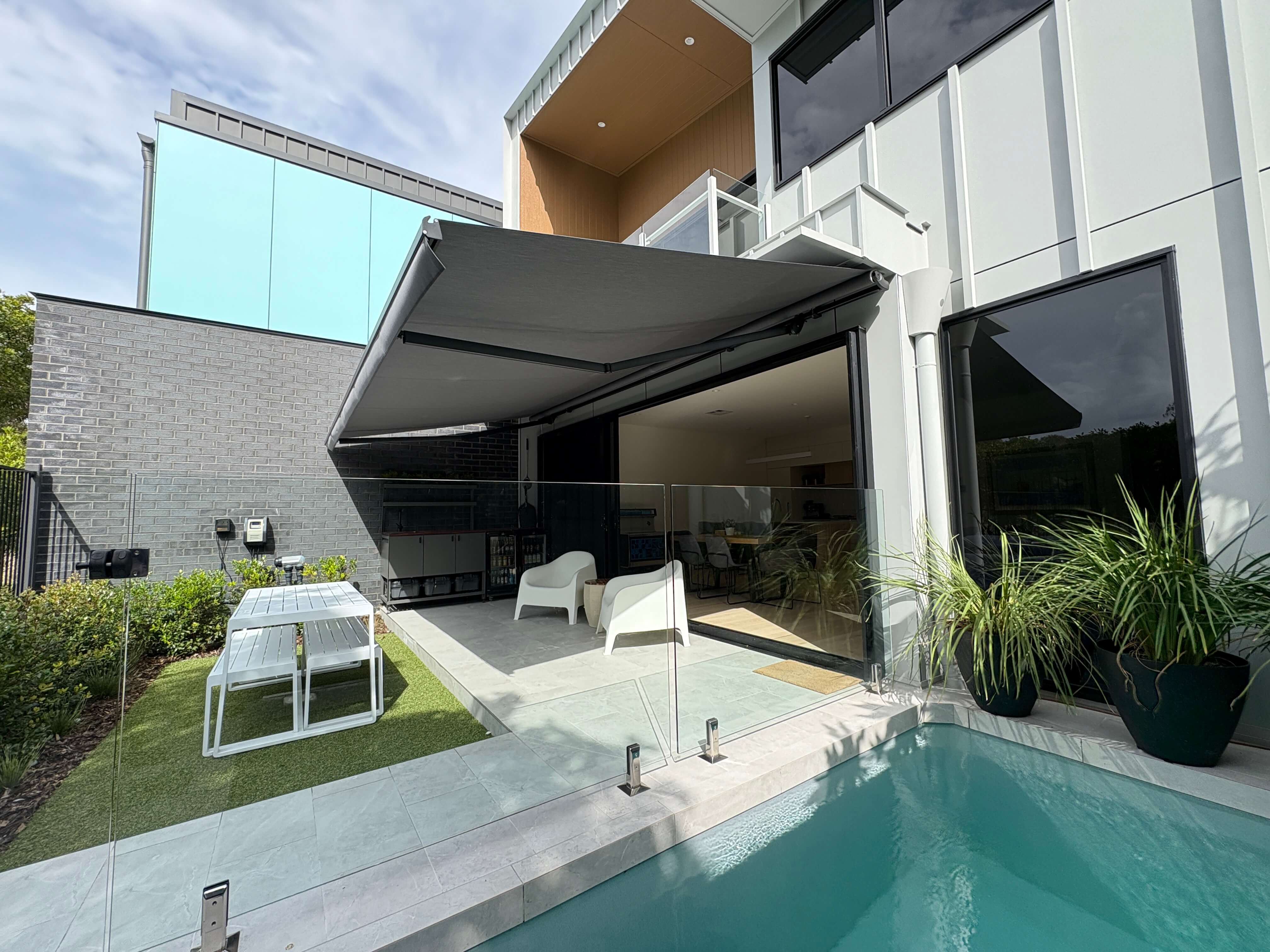 Folding arm awning over patio with pool