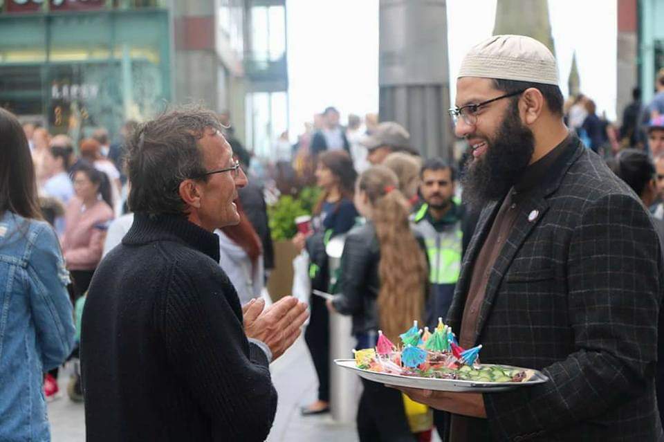 People engaging in meaningful conversations and sharing food in a public space, representing community outreach, dawah, and cultural bridge-building through genuine human connection