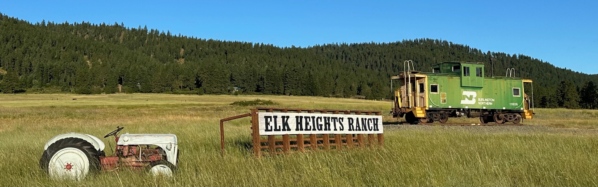 Elk Heights Ranch sign with caboose and vintage tractor